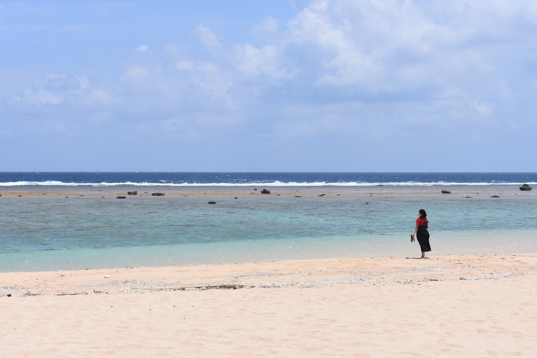 The woman walked along the beach during sightseeing tour.