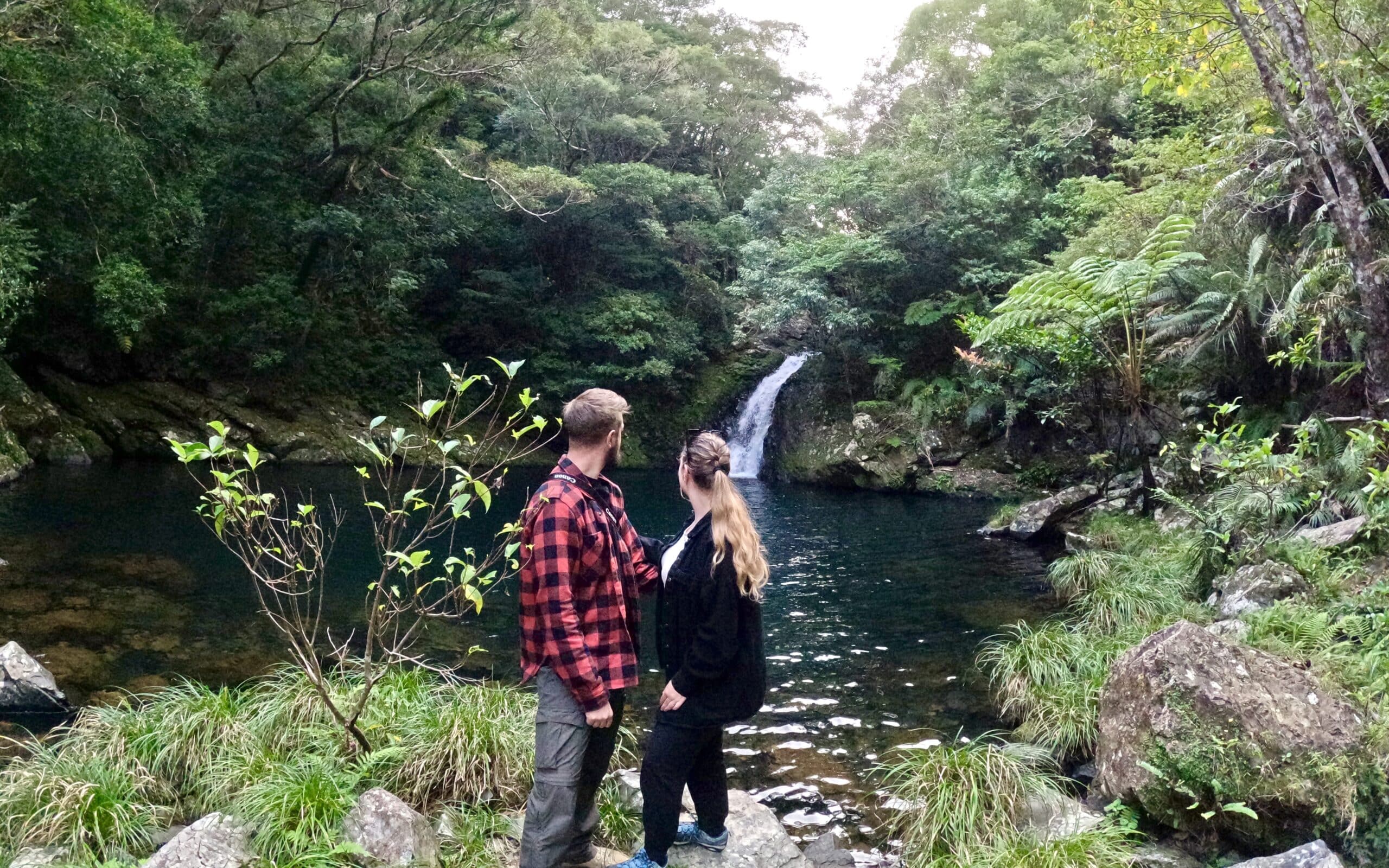 A couple enjoying the view of a waterfall.