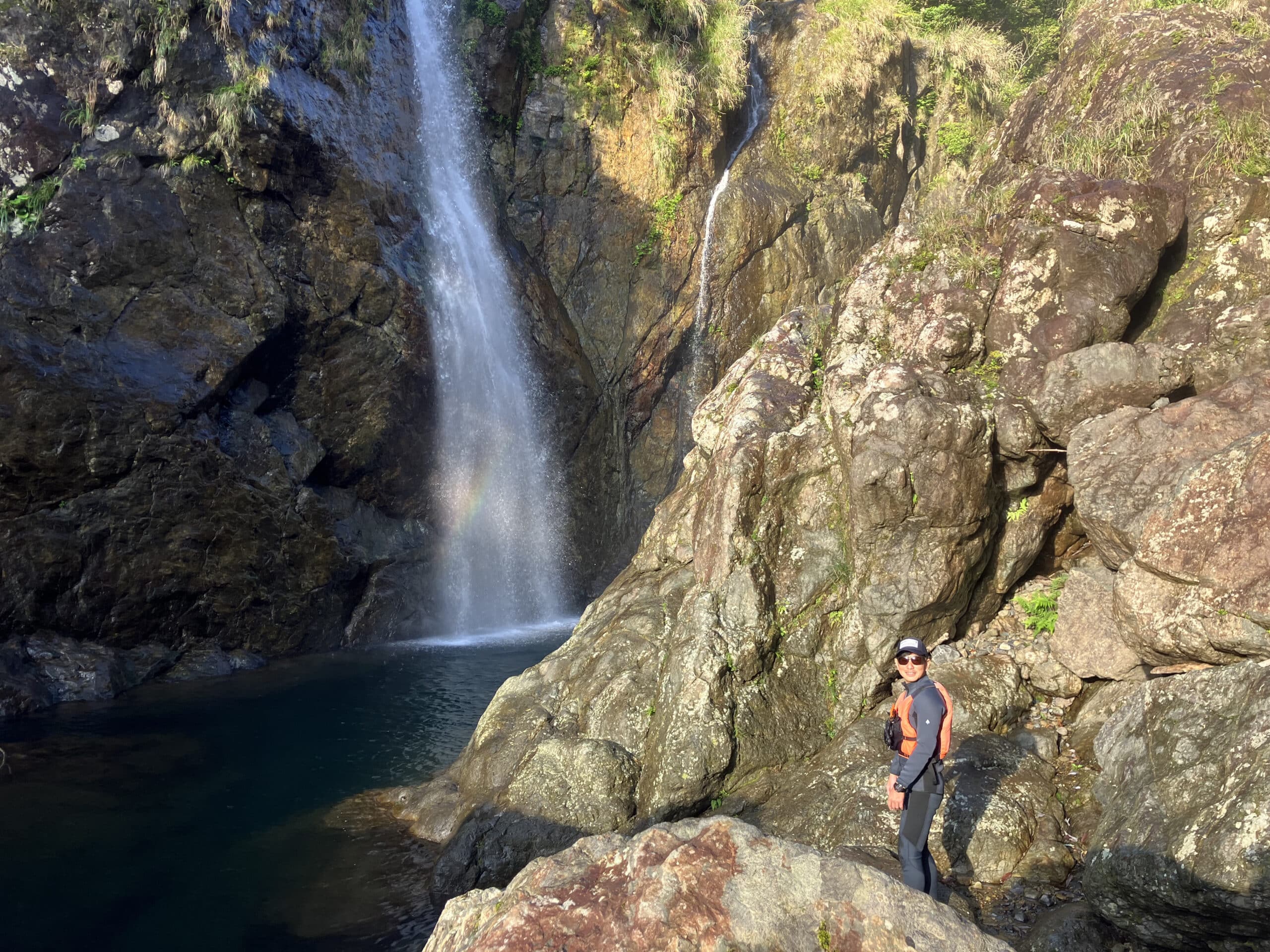 A man standing on the rocks near the waterfall.