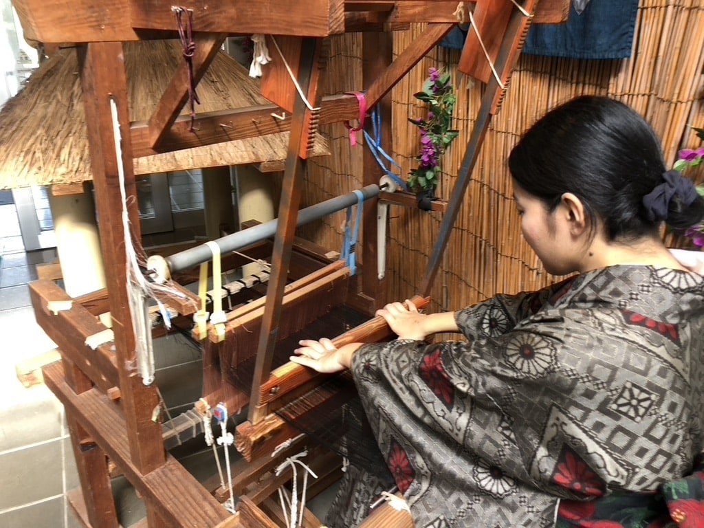 A woman is weaving Amami Oshima Tsumugi Textile.