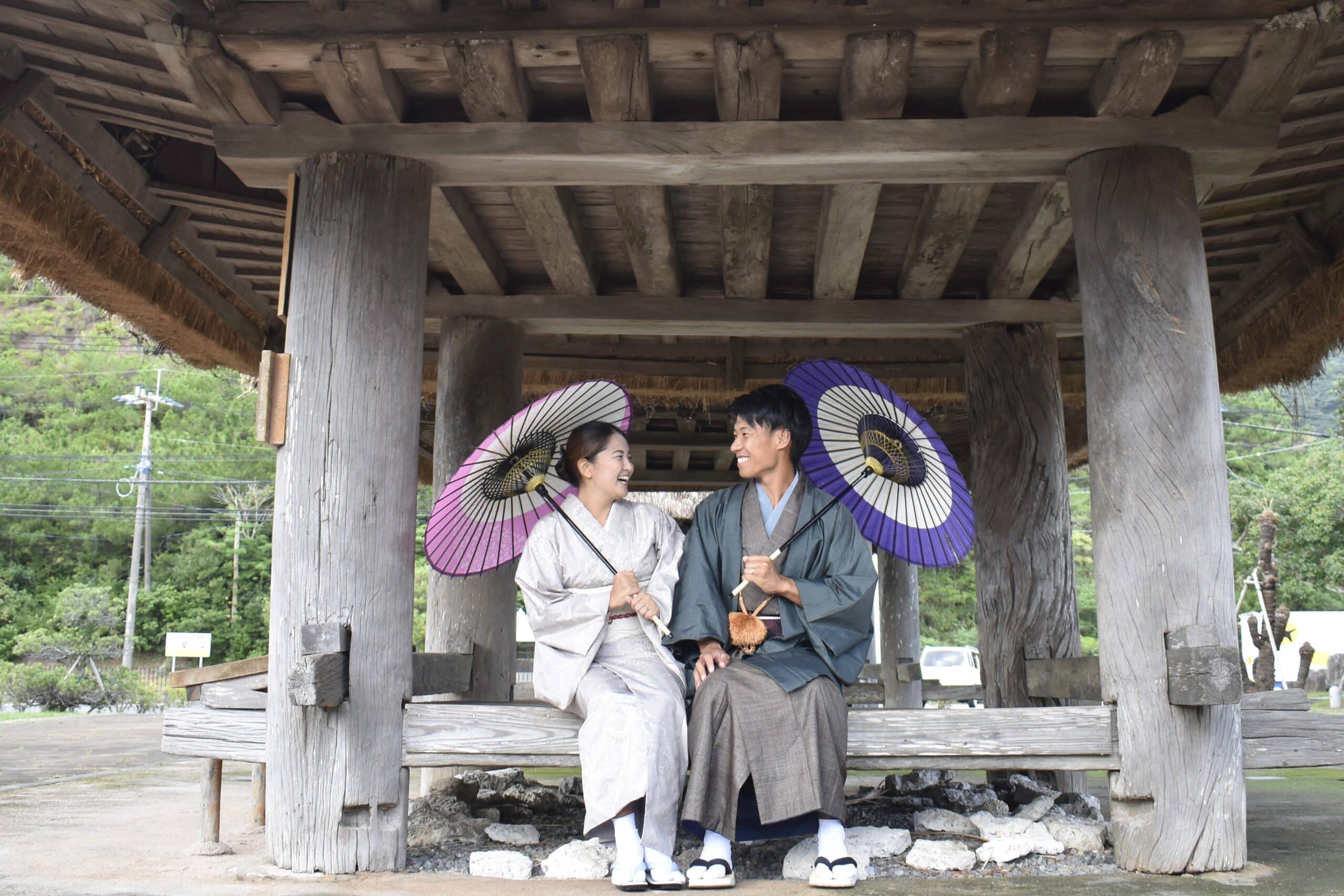 Couple wearing traditional kimono with Japanese umbrellas, experiencing cultural heritage on Amami Oshima