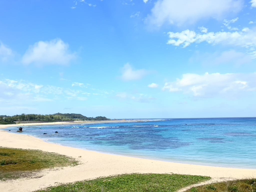 A peaceful beach with turquoise water and white sand under a bright blue sky in Tomori beach, Japan.