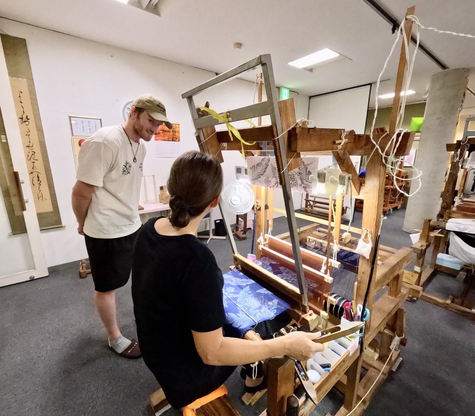 Foreign tourists observing Oshima Tsumugi weaving demonstration at a workshop in Amami Oshima