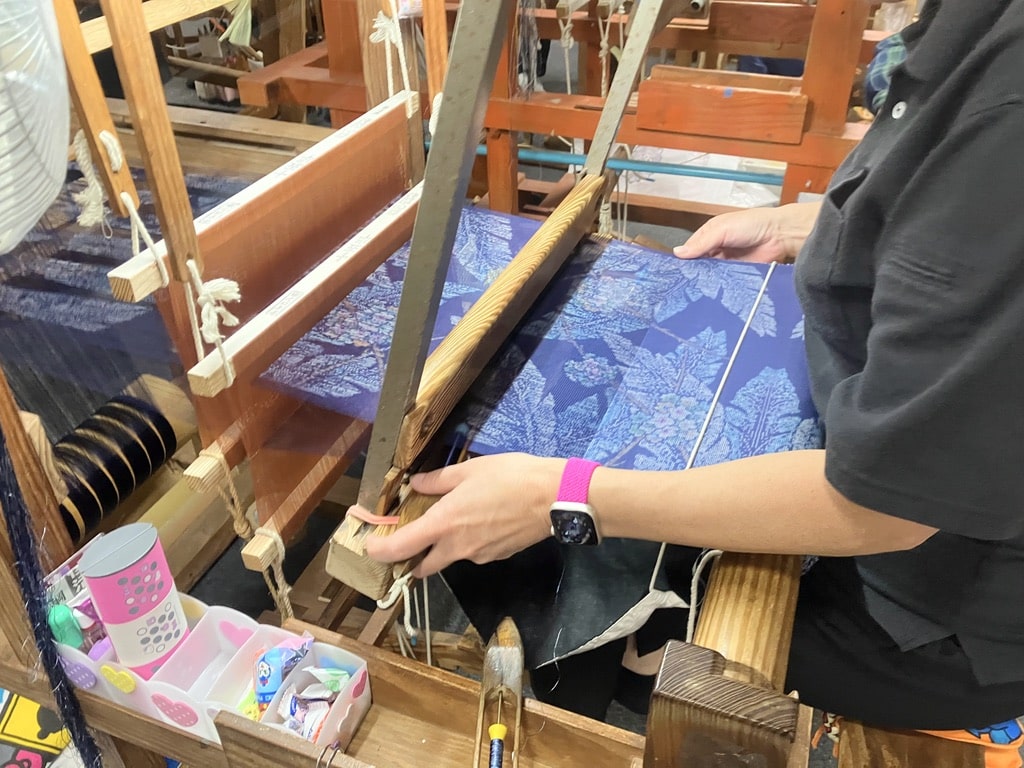 Close-up of artisan weaving Oshima Tsumugi silk fabric on a traditional loom