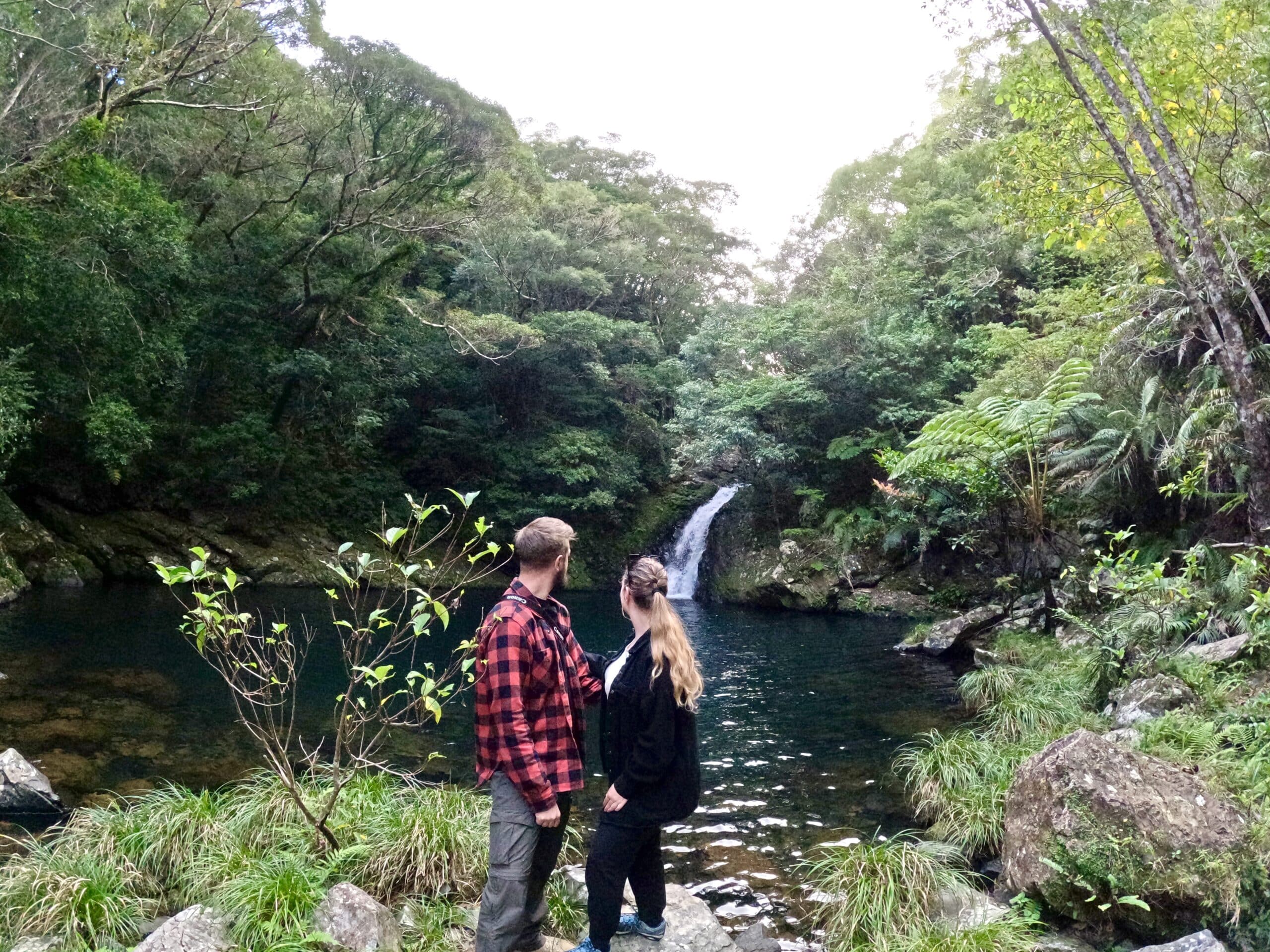 Couple enjoying a waterfall view in Amami's subtropical forest