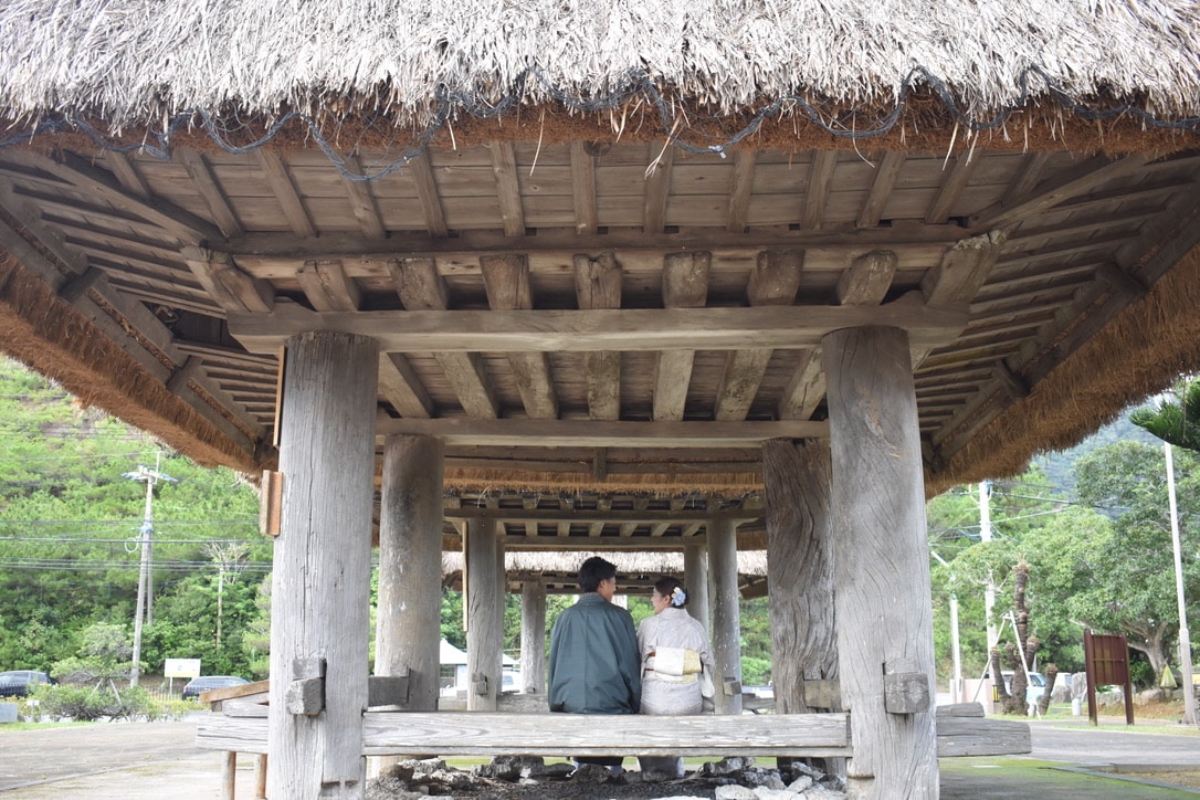 Visitor learning about Amami textile weaving on a traditional loom with guidance from a local artisan.